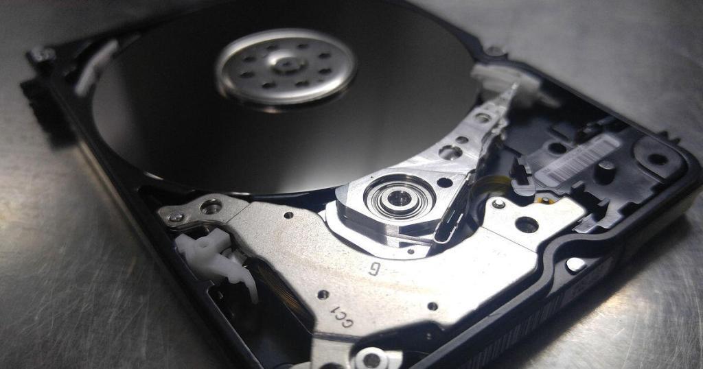 Eine ausgebaute Festplatte als Symbol für Cloud Backup mit geöffnetem Deckel liegt auf einer Metallfläche.