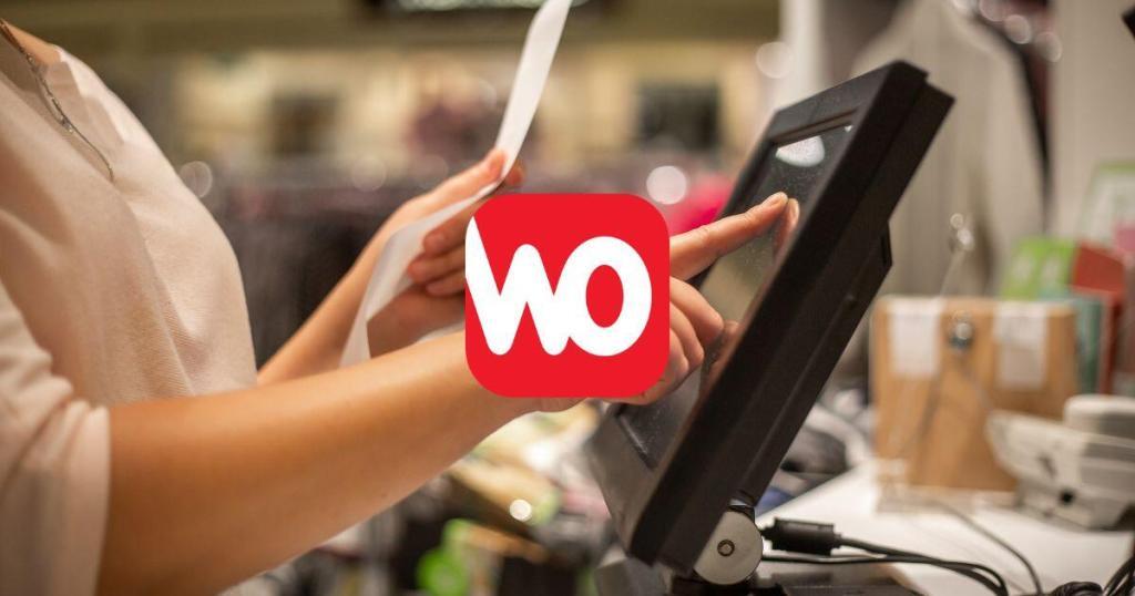 Eine Frau tippt mit der rechten Hand auf dem Display einer WinOrder Touchkasse und hält in der linken Hand einen Bon.