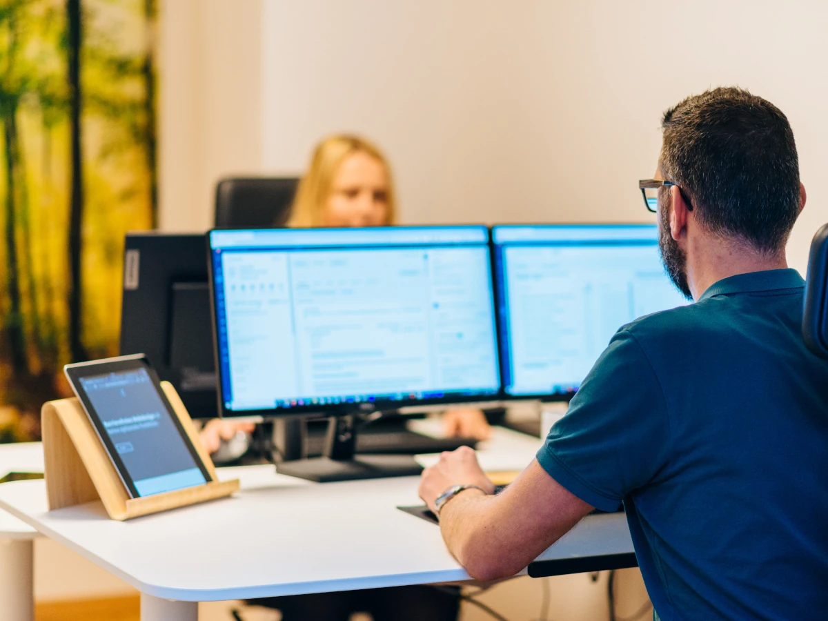 Katharina und Oliver arbeiten konzentriert gegenüber sitzend an ihren Schreibtischen