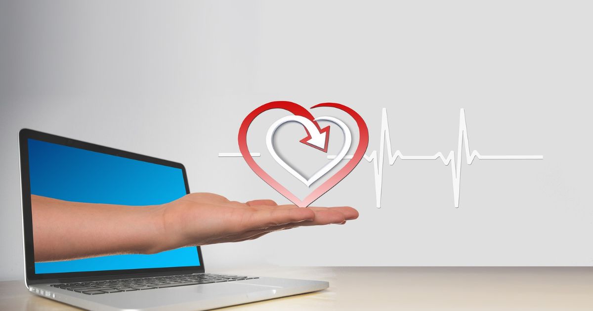Eine linke Hand greift aus einem Laptop-Bildschirm und hält ein rotes Herz mit einem Pulsschlag. Die Grafik steht sinbildlich für Online-Beratung mit Herzblut.