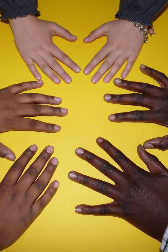 6 Hände liegen auf einem gelben Hintergrund im Kreis