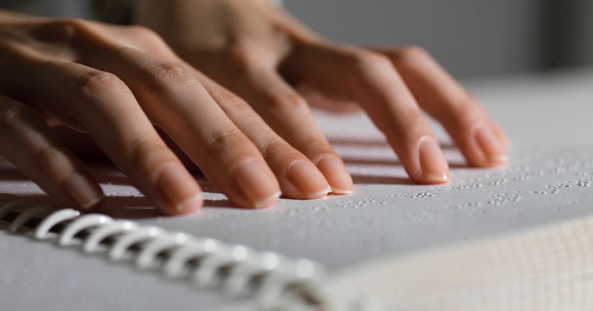 Zwei Hände lesen in einem Buch, dass in Brailleschrift, eine spezielle Blindenschrift geschrieben ist