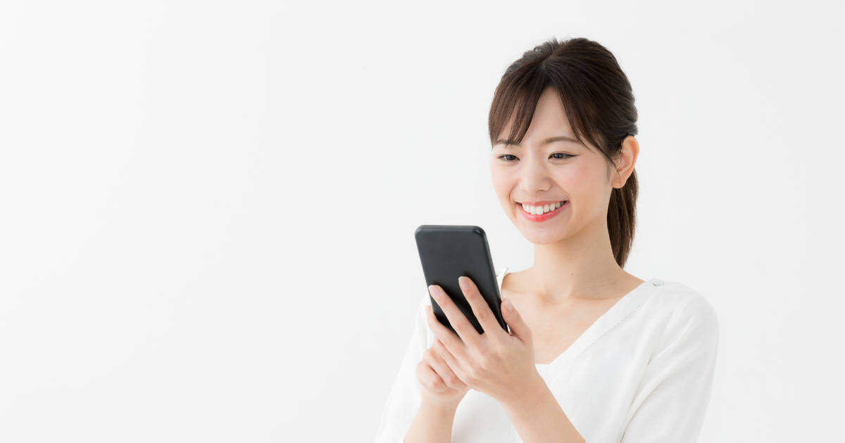 Eine lächelnde Frau mit dunkelbraunen, langen Haaren schaut auf ihr Smartphone und liest den capito Minikurs
